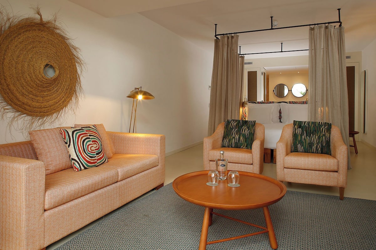 A living room with a sofa, two armchairs, a coffee table, a floor lamp, and a woven basket.