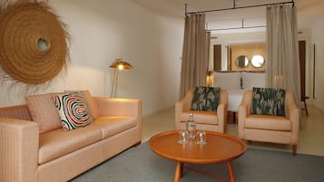 A living room with a sofa, two armchairs, a coffee table, a floor lamp, and a woven basket.