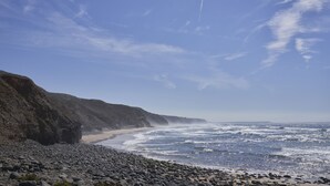 Una spiaggia rocciosa con cielo sereno e onde che si infrangono sulla riva.