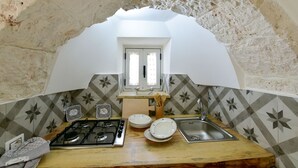 A kitchen with a stone arch, a gas stove, a sink, and patterned tiles.