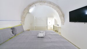 A bedroom with a bed, a television, and an arched doorway.