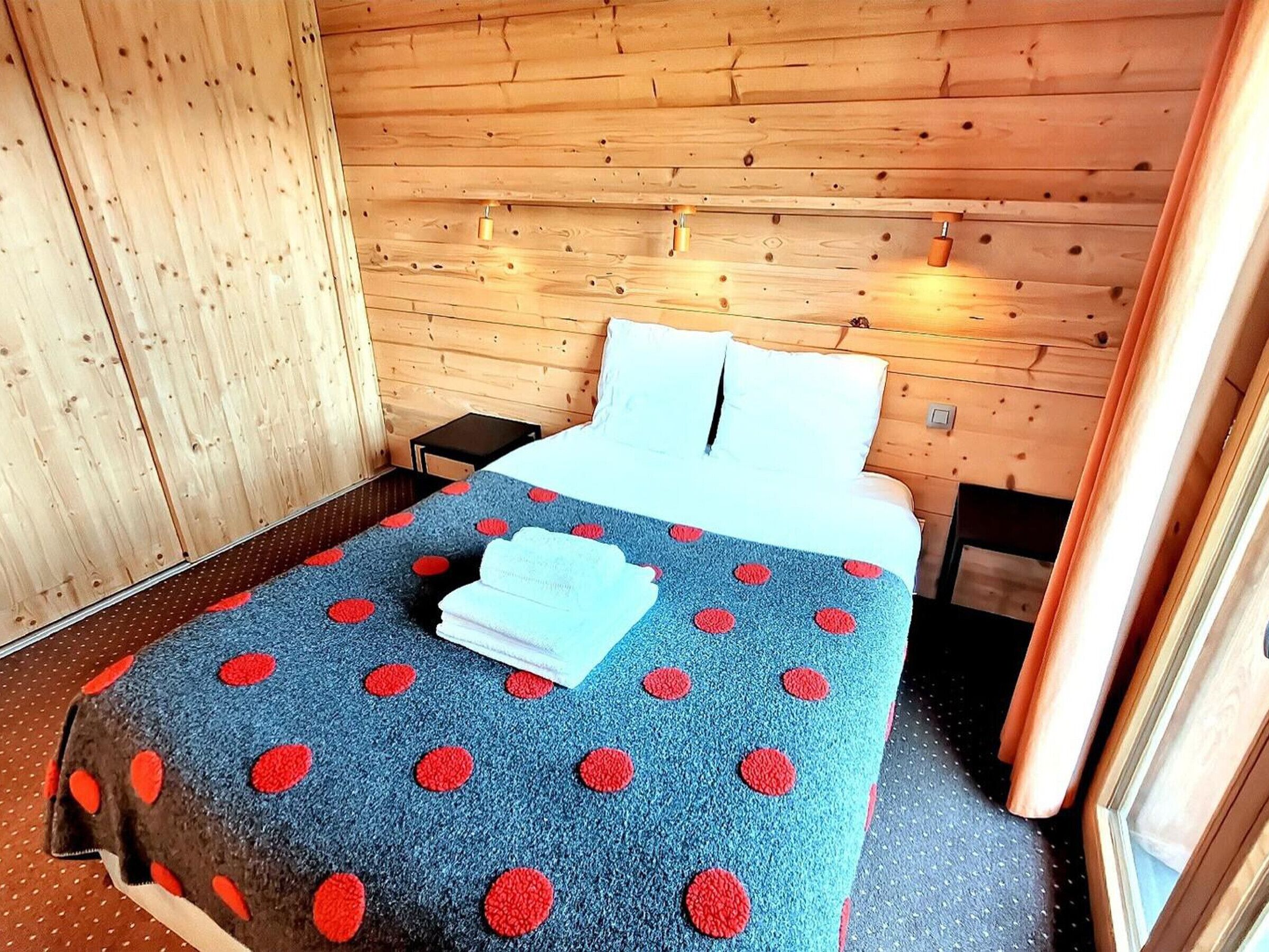 A wooden cabin room with a bed, a nightstand, and a small table.
