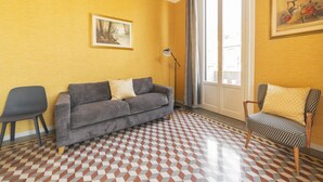 A room with a patterned floor, a grey sofa, a black chair, and a painting on the wall. - GuestHost - Zadar & Island APT! 100m from the Istria M5 stop! (Milano)