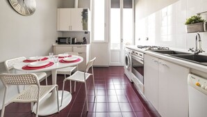 A modern kitchen with white cabinets, a built-in washing machine, and a dining area with white chairs and a round table. - GuestHost - Zadar & Island APT! 100m from the Istria M5 stop! (Milano)