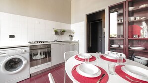 A compact kitchen with a washing machine, oven, and dining area with red placemats. - GuestHost - Zadar & Island APT! 100m from the Istria M5 stop! (Milano)