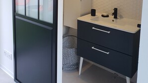 A modern bathroom with a large mirror, a black vanity, and a glass door leading to a balcony with outdoor seating. - Architect-designed villa with heated pool (Moliets et Maa)