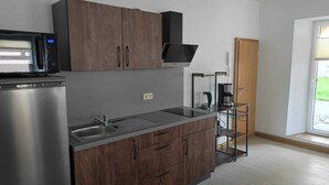 Une cuisine moderne dotée d’appareils électroménagers en acier inoxydable, de meubles en bois et d’un four à micro-ondes encastré.