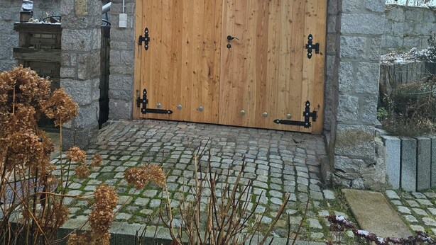 Un bâtiment en bois doté d’une grande porte à deux battants, de murs en pierre et d’une entrée pavée.