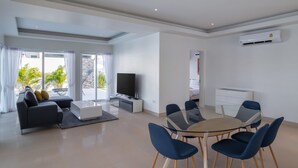 Ein modernes Wohnzimmer mit einer Couch, Fernseher, Esstisch und Stühlen.