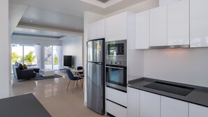 Eine moderne Küche mit weißen Schränken, Edelstahlgeräten und einem Essbereich mit einer Couch und Stühlen.