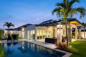 Een modern huis met zwembad, overdekt terras en een verzorgd gazon.