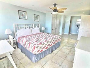 Une chambre d’hôtel équipée d’un lit, d’un bureau, d’une chaise, d’un ventilateur de plafond et d’une armoire.