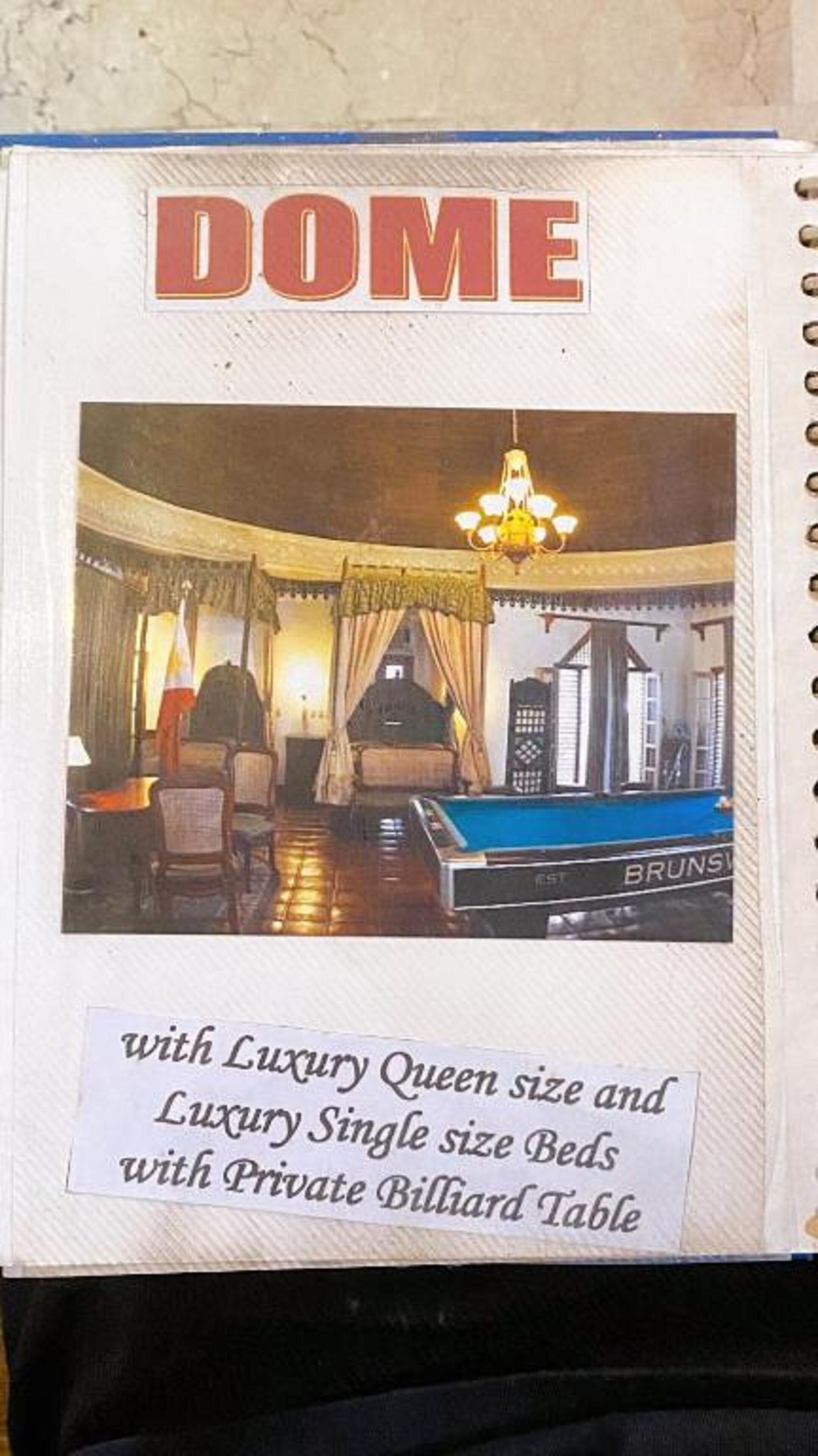 A brochure page for a hotel named "DOME" featuring a luxurious room with a private billiard table.