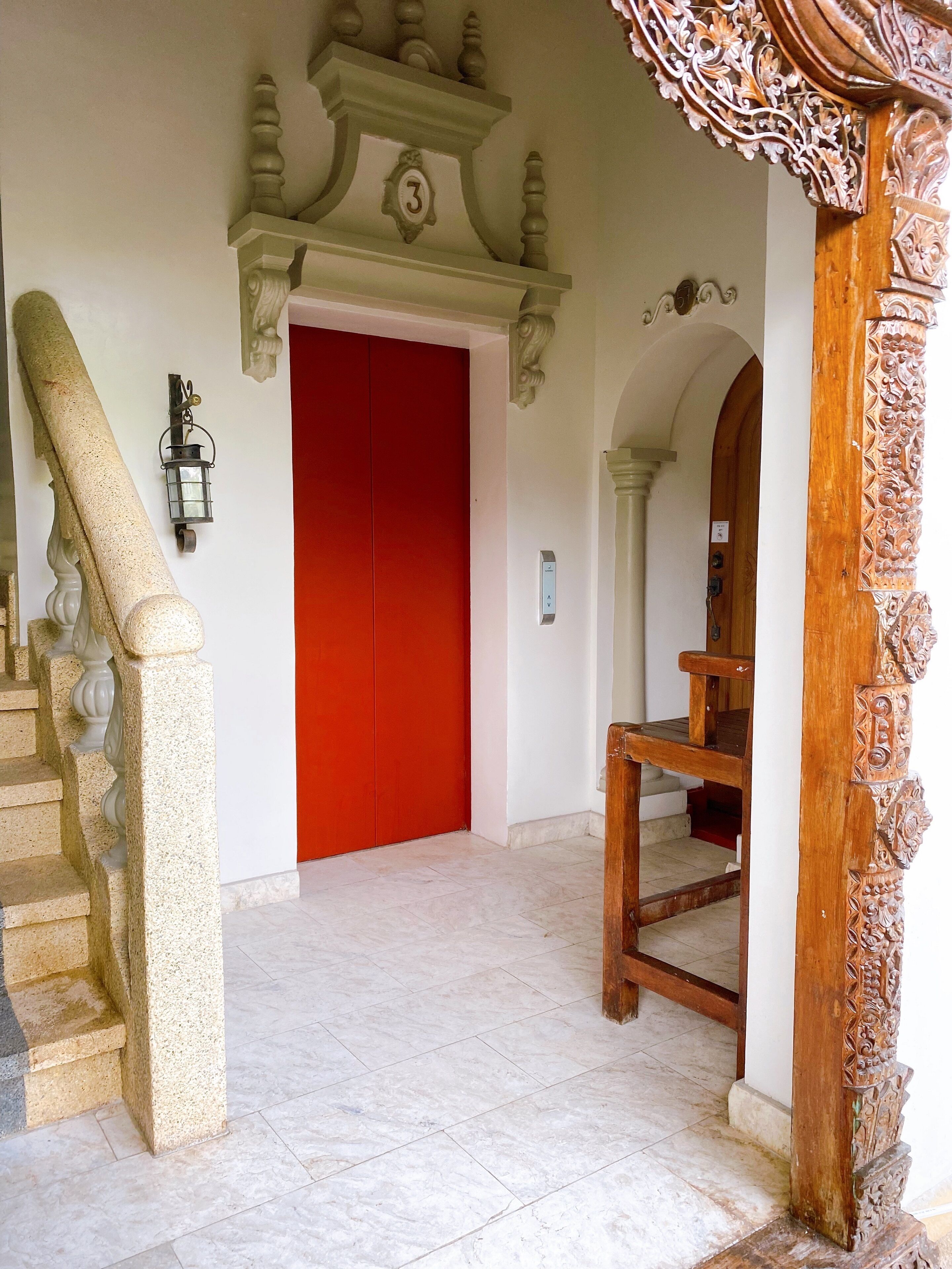 A staircase with a handrail, a red door, and a wooden bench.