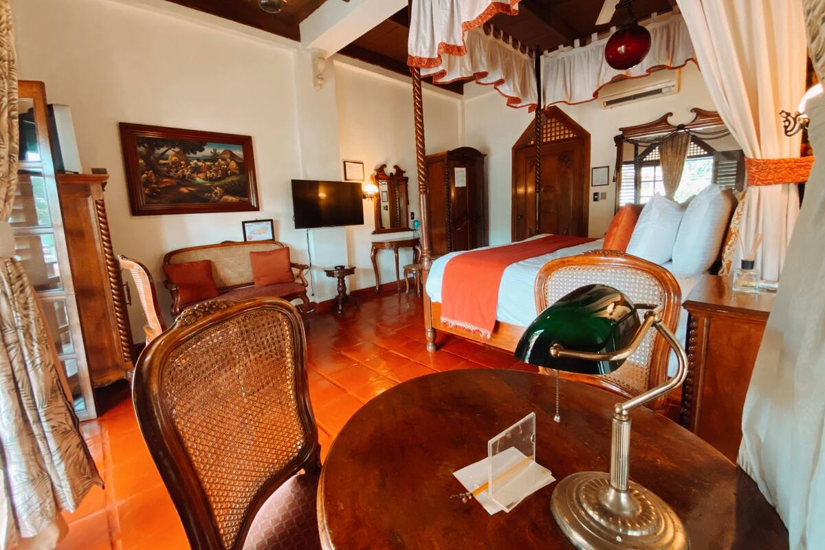 Ein traditionell eingerichtetes Zimmer mit Bett, Fernseher, Holztisch und Stuhl.