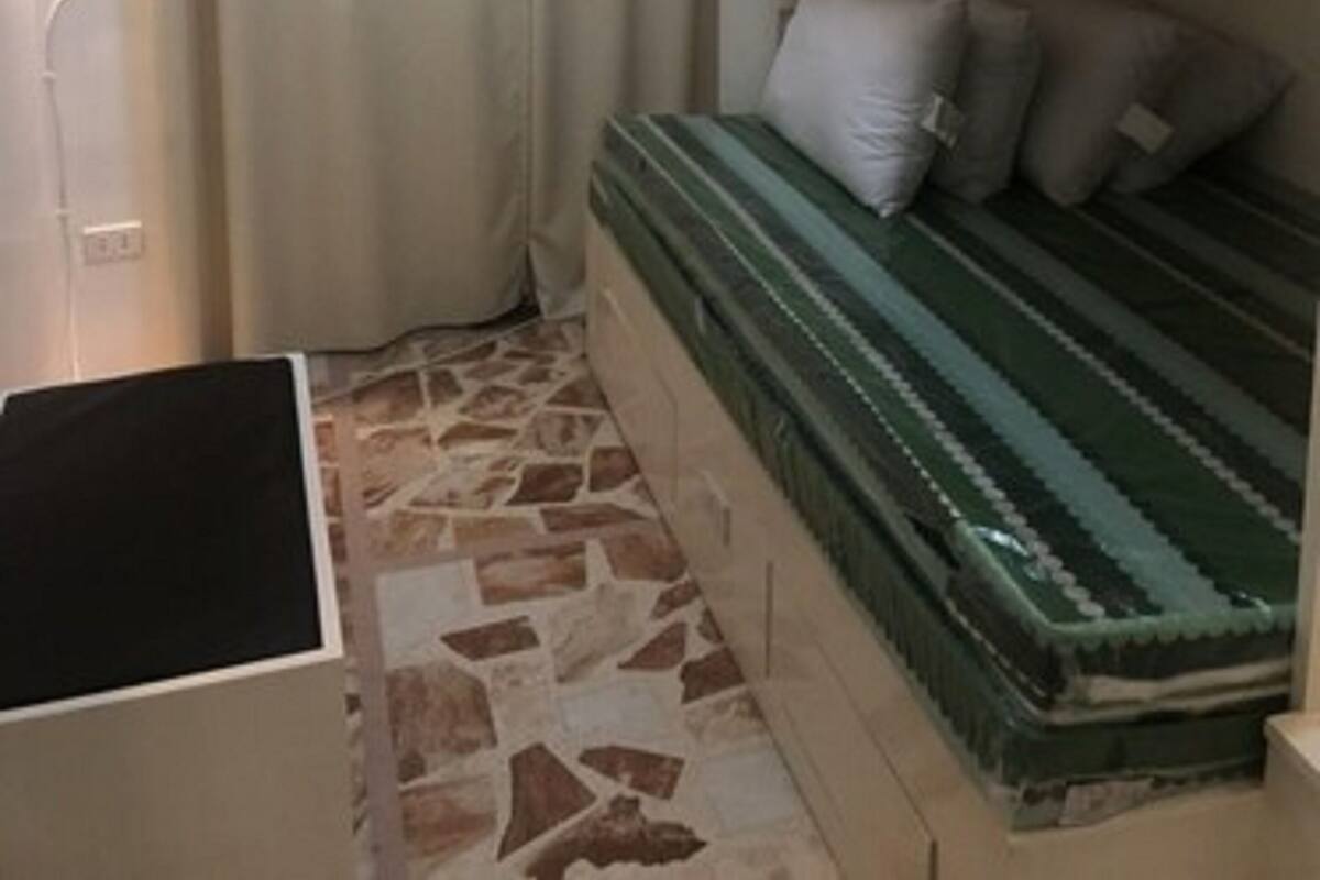 Ein Zimmer mit Etagenbetten, einem Vorhang, Fliesenboden und einer Klimaanlage.