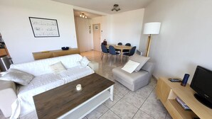 A modern living room with a sofa, a coffee table, a TV stand, and a dining area with chairs and a table. - T2 apartment with terrace, 500m from the beach, Les Sables-d'Olonne (Les Sables-d'Olonne)