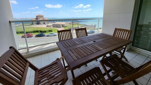 A balcony with a wooden table and chairs, a view of a coastal area with buildings and cars. - T2 apartment with terrace, 500m from the beach, Les Sables-d'Olonne (Les Sables-d'Olonne)