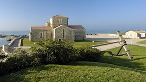 A stone church with a bell tower, a grassy area, and a view of the sea. - T2 apartment with terrace, 500m from the beach, Les Sables-d'Olonne (Les Sables-d'Olonne)