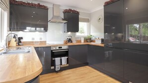 Eine moderne Küche mit dunklen Schränken, einer Holz Arbeitsplatte, einem eingebauten Backofen und einem Edelstahl-Kühlschrank.