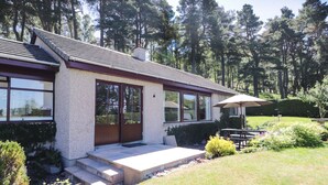 Ein zweistöckiges Haus mit einer Steinfassade, großen Fenstern und einer überdachten Terrasse.