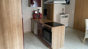 Een compacte keuken met een centraal eiland, een magnetron, een broodrooster en een fornuis.
