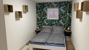 Een slaapkamer met een bed, een wandplank en een ingelijste foto.