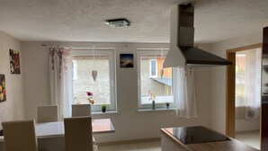 Een moderne keuken met een eethoek, grote ramen en uitzicht op buiten.