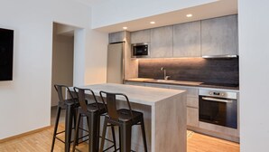 Una cocina moderna con una isla central, taburetes de bar, un microondas, un horno y un fregadero.