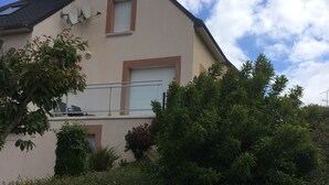 A two-story house with a sloped roof, satellite dishes, and a small balcony.