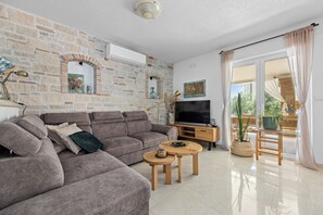 A living room with a sofa, two coffee tables, a TV, and a potted plant.