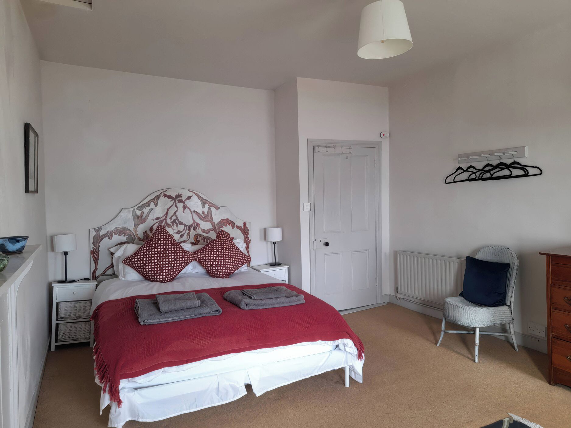 Une chambre à coucher comprenant un lit, une table de chevet, une chaise, une commode et un radiateur.
