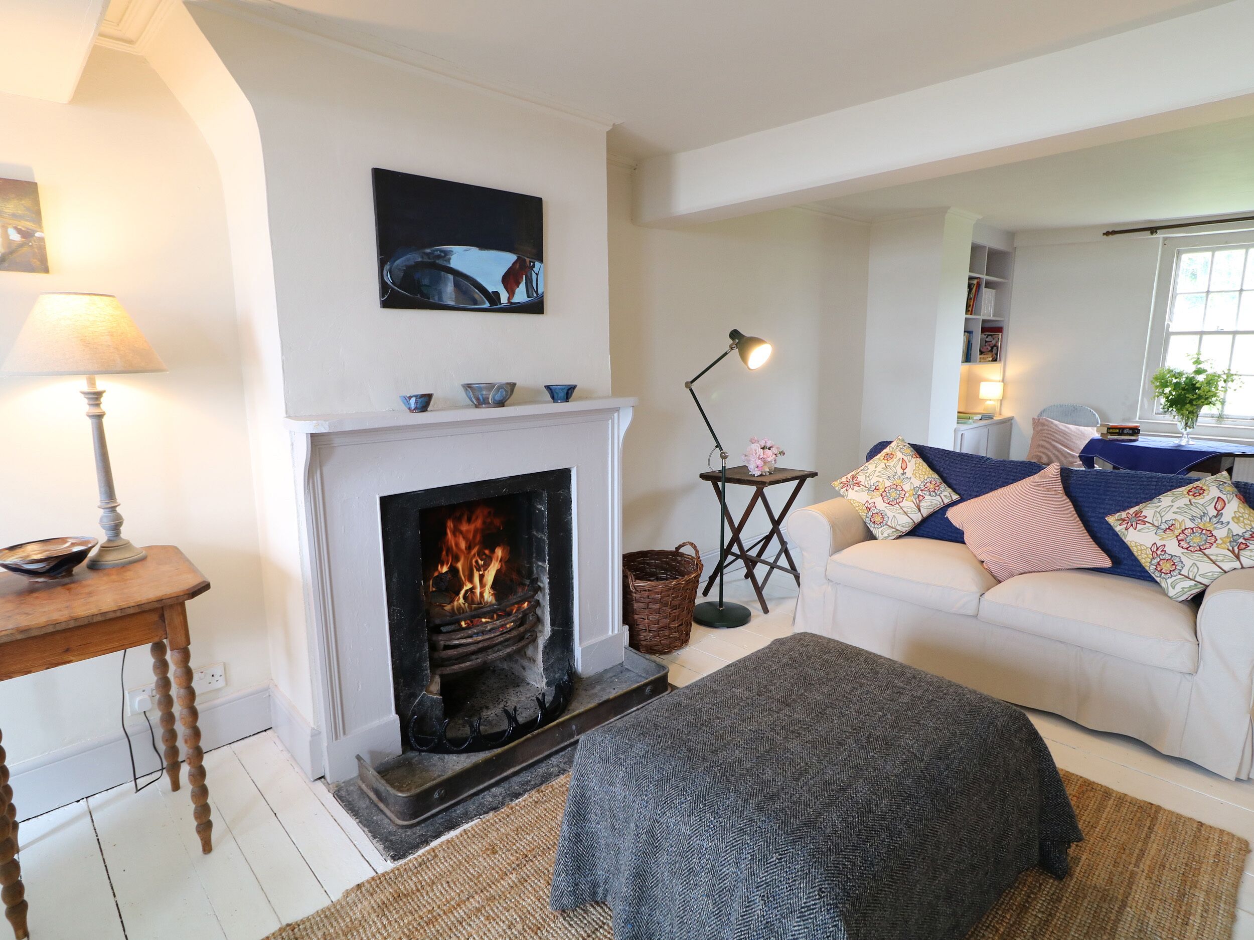 A cozy living room with a fireplace, a sofa, a lamp, and a painting on the wall.