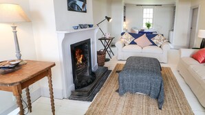 A living room with a fireplace, a sofa, a coffee table, and a lamp. - The Ferry House (Ramelton)