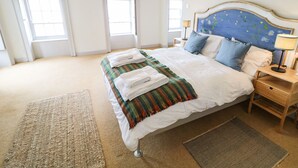 A bedroom with a large bed, a nightstand, a lamp, and a view of the outside through a window. - The Ferry House (Ramelton)