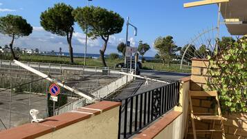 A balcony with a view of the sea, a no parking sign, and a wooden chair.