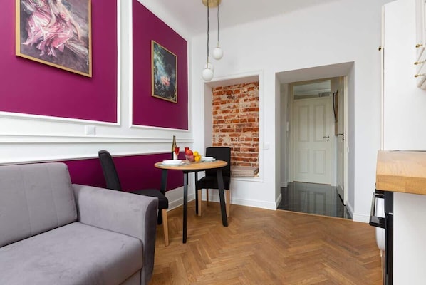 Un área de comedor con una mesa y sillas, un sofá y una pared de ladrillo.