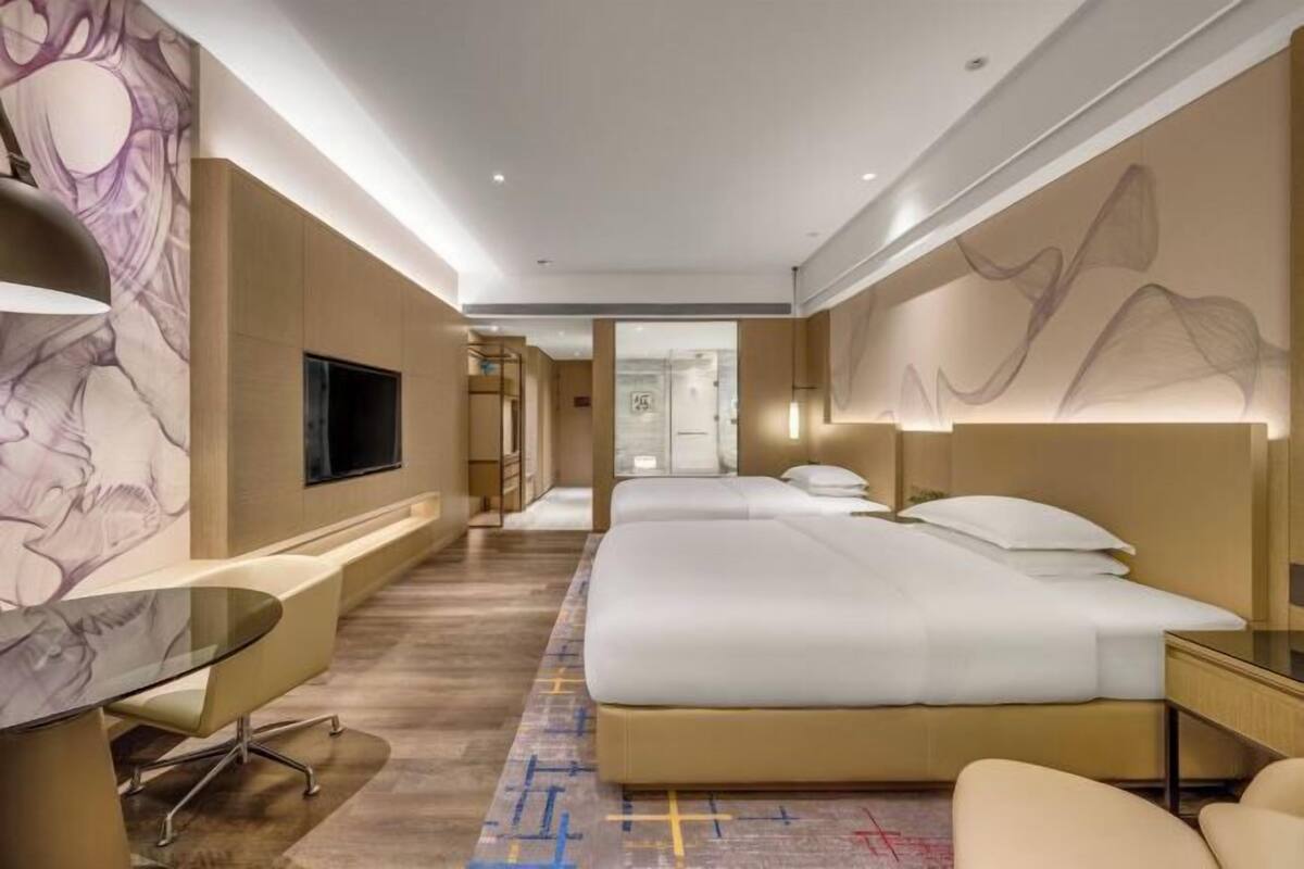 Una habitación de hotel con una cama grande, un escritorio, una silla y un televisor.