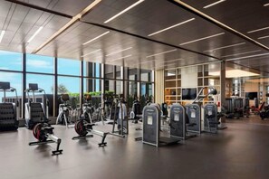 Een moderne sportschool met diverse fitnessapparaten, grote ramen en een schoon, goed verlicht interieur.