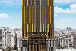Un edificio moderno de gran altura, con un llamativo diseño vertical y un amplio área de entrada.