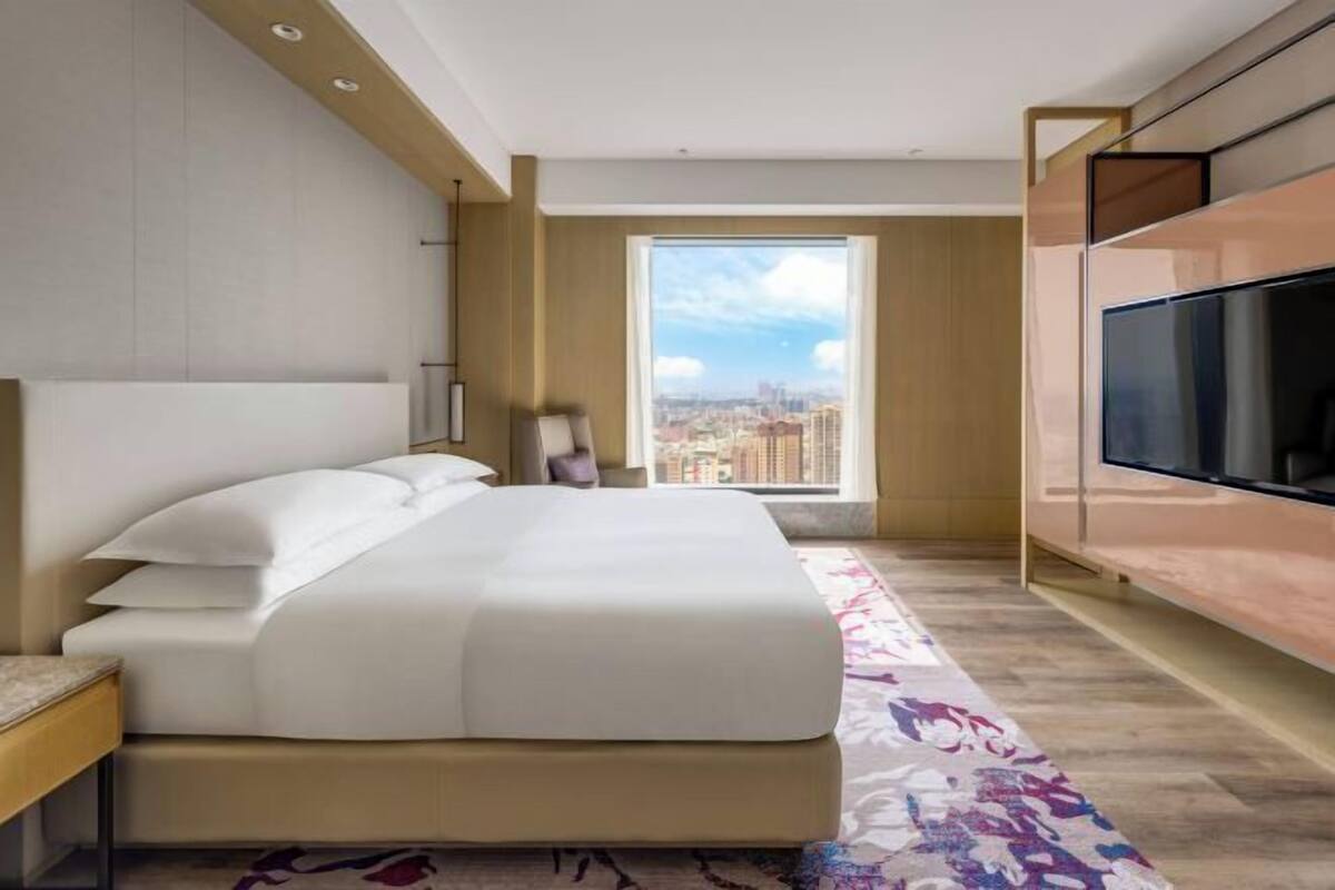 Una habitación de hotel moderna con una cama grande, televisión y vistas a la ciudad.
