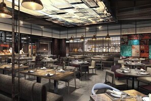 L’intérieur d’un restaurant moderne, avec plusieurs tables et chaises, un bar et une cuisine en arrière-plan.