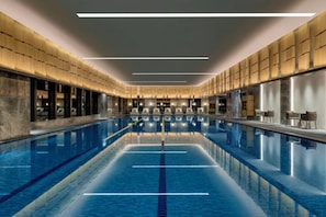Een lang binnenzwembad met duidelijke banen, omringd door zitgedeeltes en een modern architectuur.
