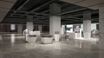 A spacious indoor area with high ceilings and a polished floor, featuring several white seating areas and a reception desk.