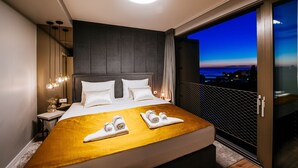 Habitación de hotel moderna con una cama grande, un balcón con vistas a la ciudad y un techo bien iluminado.