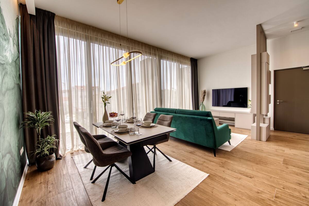 A modern living room with a dining table, chairs, a sofa, and a TV.