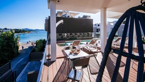 Un balcón con piscina, sillas de descanso y una mesa de comedor con una bandeja de comida.