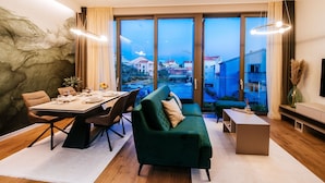 Una sala de estar moderna con comedor, ventanas amplias y vista a un pueblo.