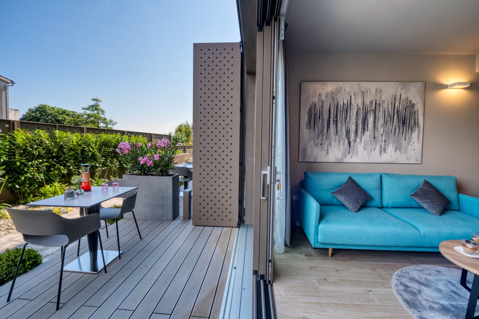 An outdoor patio with a table and chairs, a blue sofa, and a painting on the wall.