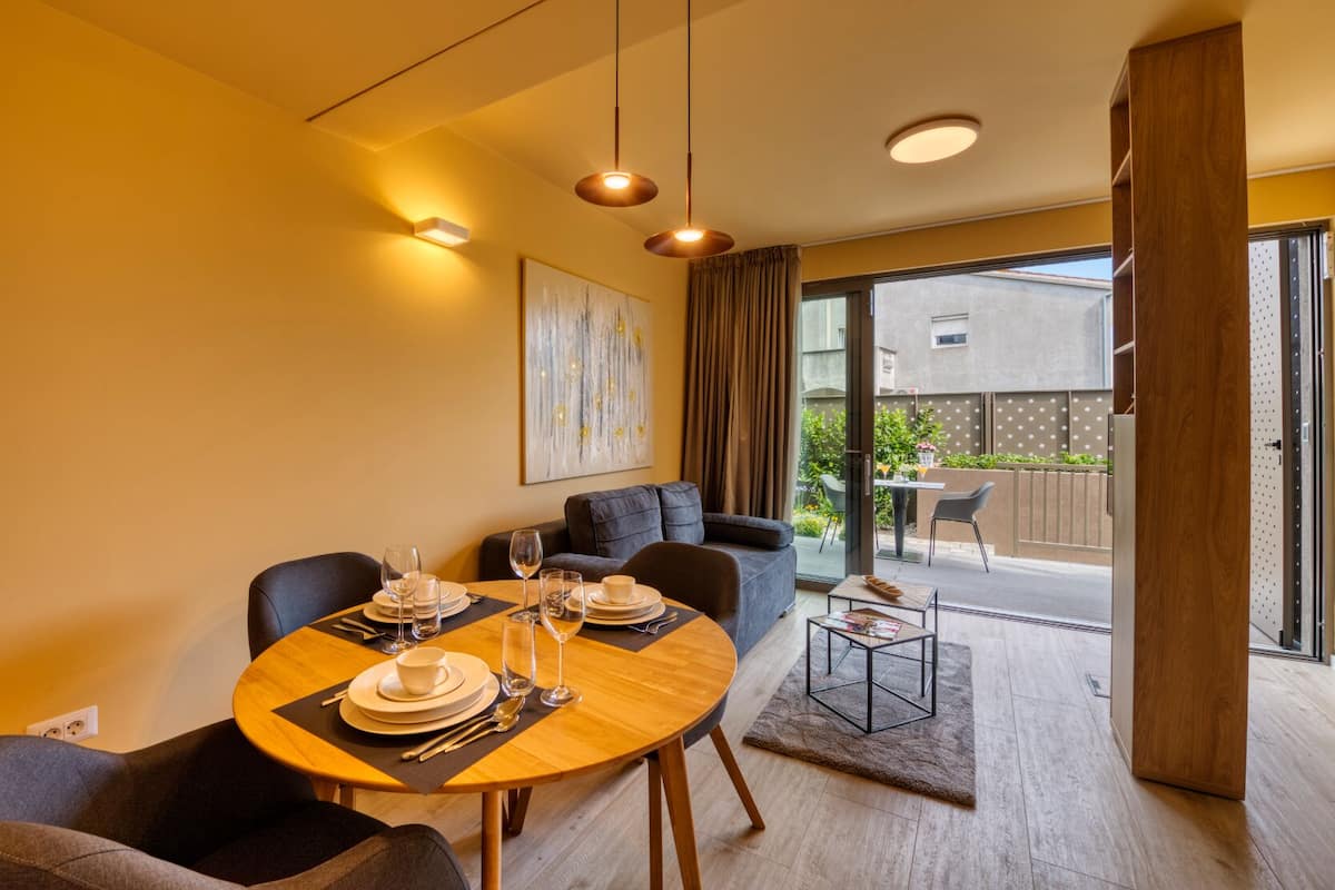 A modern dining area with a wooden table set for four, a sofa, and a small coffee table.